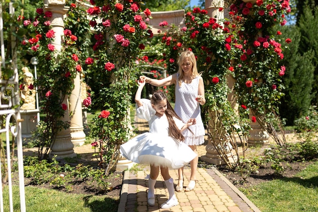 Young mother walking with her little daughter in the rose garden Portrait mom with child together