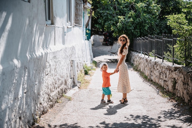 A young mother walks by the hand with her little son Active recreation Fresh air