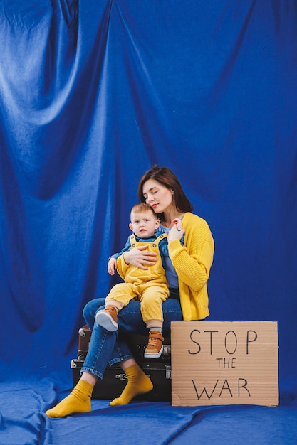 A young mother with a baby in her arms on a blue background protesting against the war between Russia and Ukraine Ukrainian woman asks to stop the war