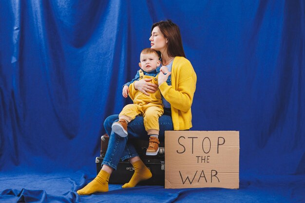 A young mother with a baby in her arms on a blue background protesting against the war between Russia and Ukraine Ukrainian woman asks to stop the war