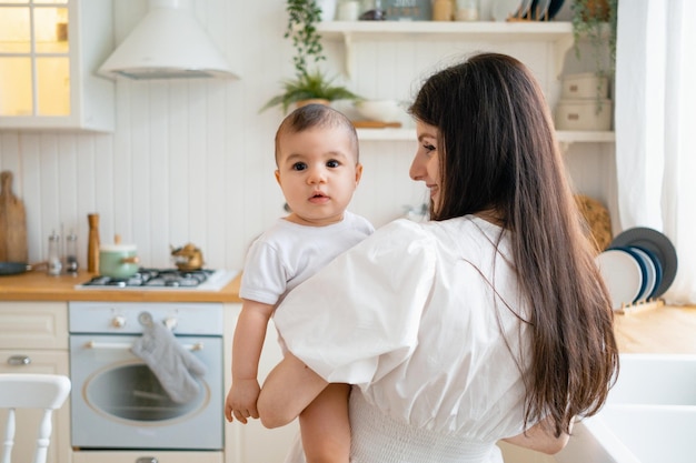 A young mother with her child in the kitchen The kid looks at the cameraxDxA