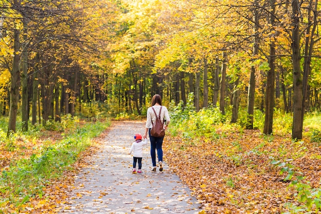 Young mother with her little baby girl in the autumn park.