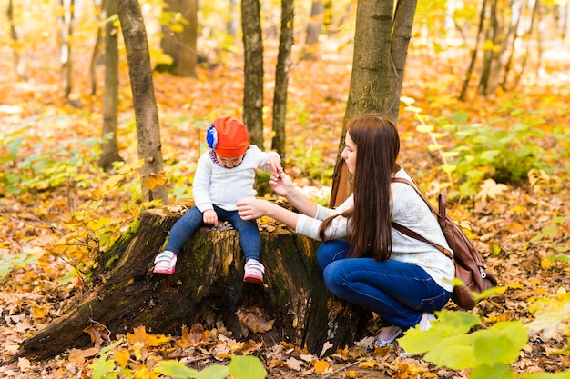 Young mother with her little baby girl in the autumn park.