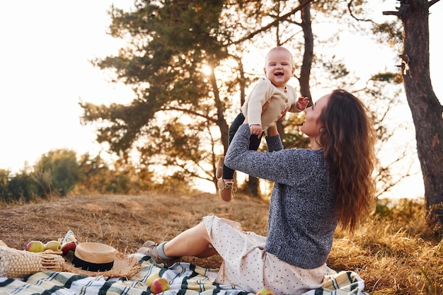 Young mother with her little baby rests outdoors at autumn season