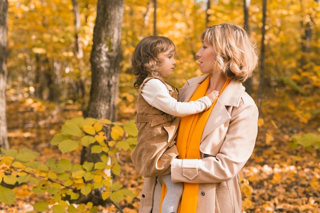 Young mother with her little daughter in an autumn park fall season parenting and children concept