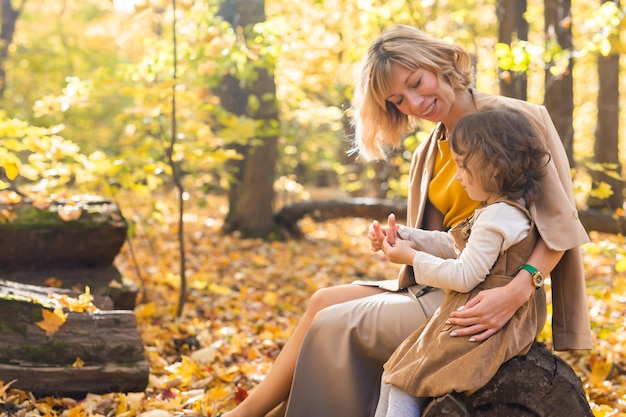 Young mother with her little daughter in an autumn park Fall season parenting and children concept