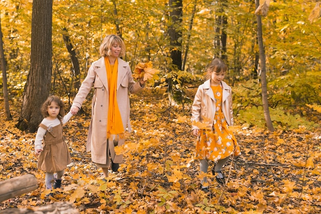 Young mother with her little daughters in an autumn park fall season parenting and children concept