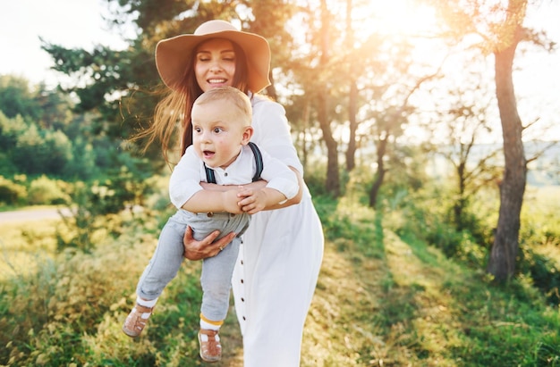 Young mother with her little son is outdoors in the forest Beautiful sunshine