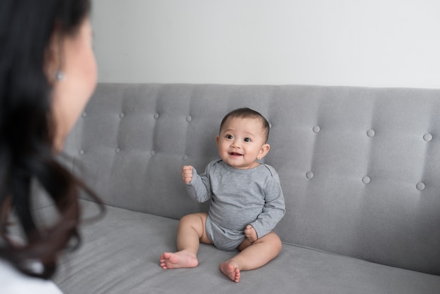 Young mother with her one years old little son dressed in pajamas are relaxing and playing in the living room at the weekend together, lazy morning, warm and cozy scene. Selective focus.