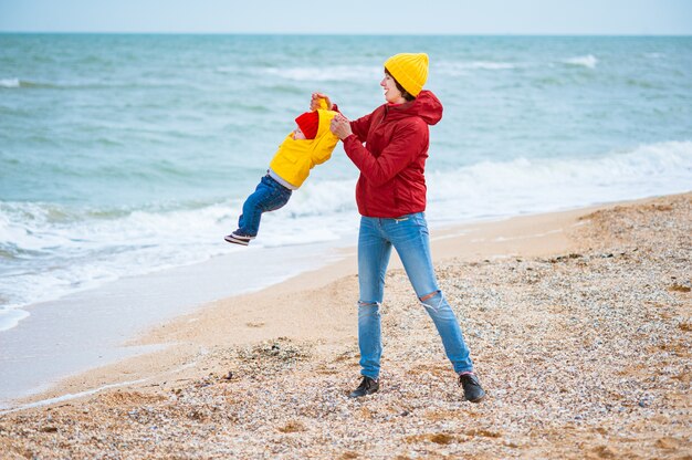 Young mother with her son at the seashore in winter