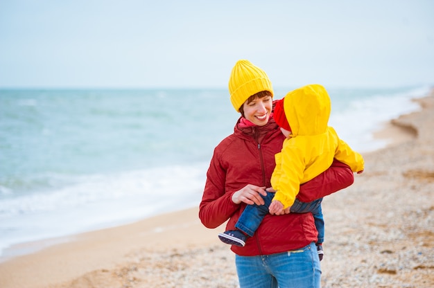 Young mother with her son at the seashore in winter