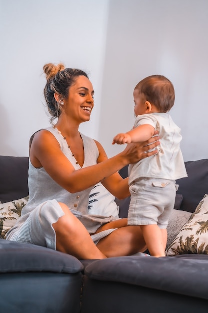 Young mother with her son sitting on the black sofa in their home