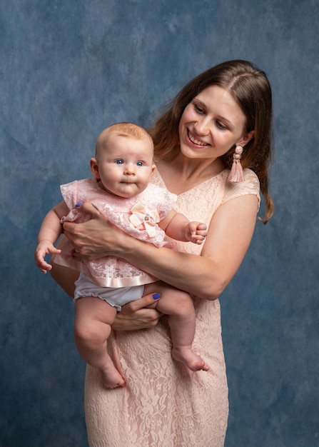 A young mother with long hair in a light dress holds a newborn daughter in her arms Mom's love