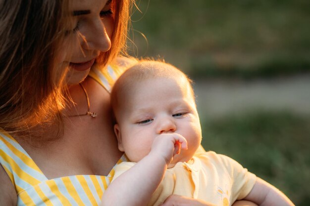 Young mother with newborn baby son on sunset nature background motherhood mother love parenthood