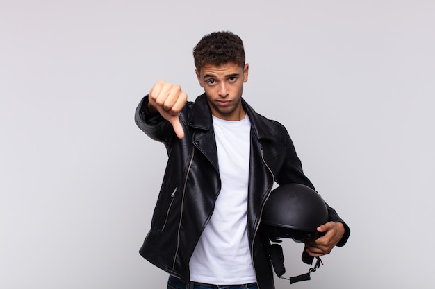 Young motorbike rider feeling cross, angry, annoyed, disappointed or displeased, showing thumbs down with a serious look