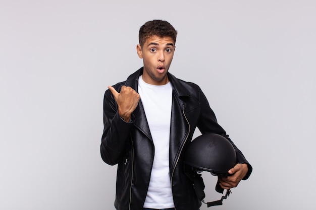 Young motorbike rider looking astonished in disbelief, pointing at object on the side and saying wow