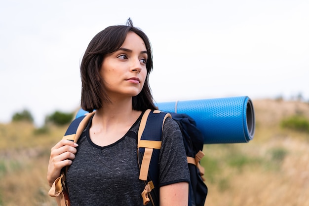 Young mountaineer girl with a big backpack at outdoors