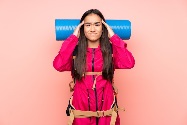 Young mountaineer Indian girl with a big backpack isolated on pink background unhappy and frustrated with something. Negative facial expression