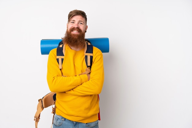 Young mountaineer man with a big backpack over isolated white wall laughing