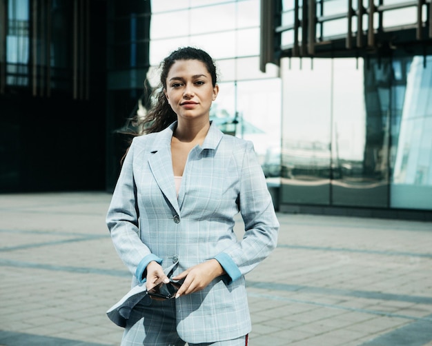 A young mulatto woman against the background of a business center is holding a mobile phone and talking