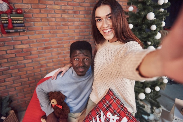 Young multiethnic couple meeting Christmas hugging home. New Year. Festive mood of a man and a woman