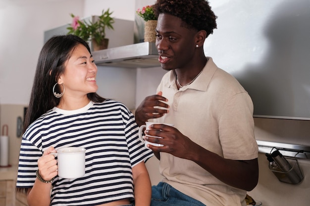 Young multiracial couple taking a break hugging and talking in the kitchen Concept Lifestyle bonding love