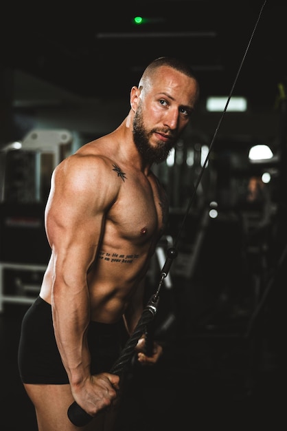 A young muscular bodybuilder man doing hard training for his arms muscles at the gym.