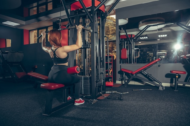 Young muscular caucasian woman practicing in gym with equipment wellness healthy lifestyle