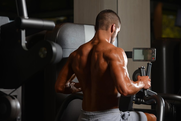 Young Muscular Fitness Bodybuilder Doing Heavy Weight Exercise For Back On Machine In The Gym