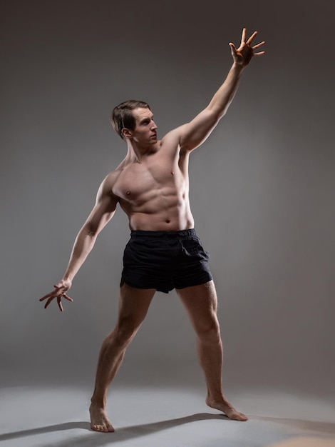 Young muscular man in an expressive pose artistic pose of the hero with outstretched arms beautiful