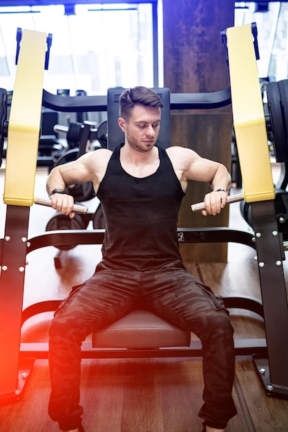 Young muscular man training hard in the gym Handsome man with nice biceps workout