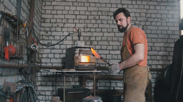 Photo young muscular man working on a blacksmith with metal, wide angle