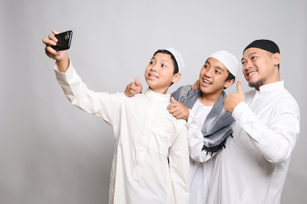 Young Muslim Boy Taking Selfie On Mobile Phone With His Brother And Father