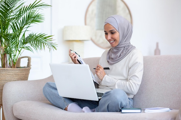 Young muslim business woman recruiter in hijab working remotely from home via laptop sits on the