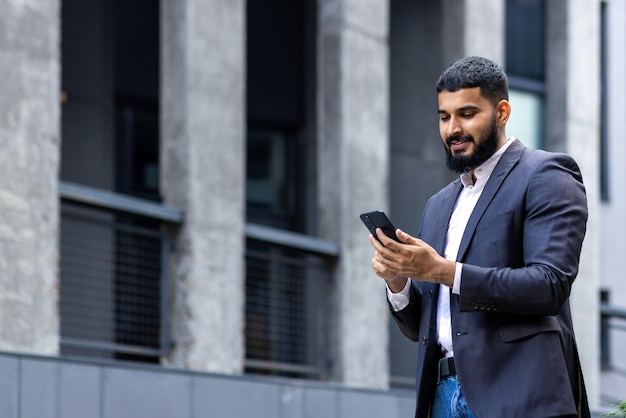 Young muslim man businessman standing on the street near an office building and using the phone