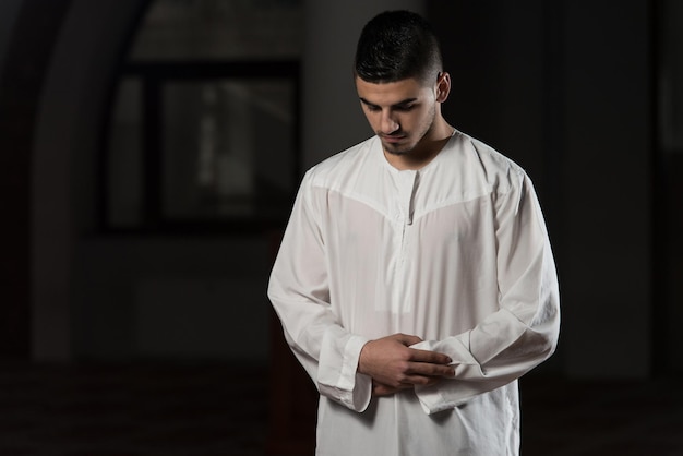 Young Muslim Man Making Traditional Prayer To God While Wearing A Traditional Cap Dishdasha