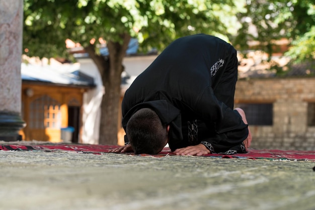 Young Muslim Man Making Traditional Prayer To God While Wearing A Traditional Cap Dishdasha