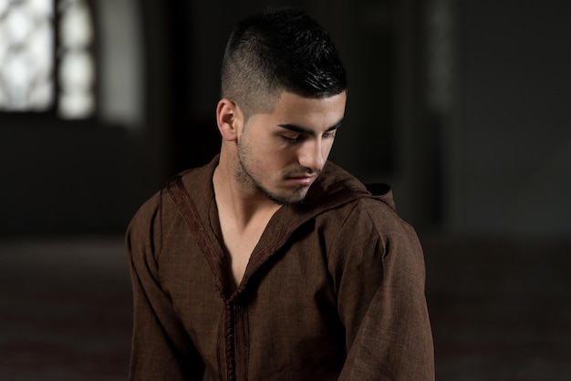 Young Muslim Man Making Traditional Prayer To God While Wearing A Traditional Cap Djellaba