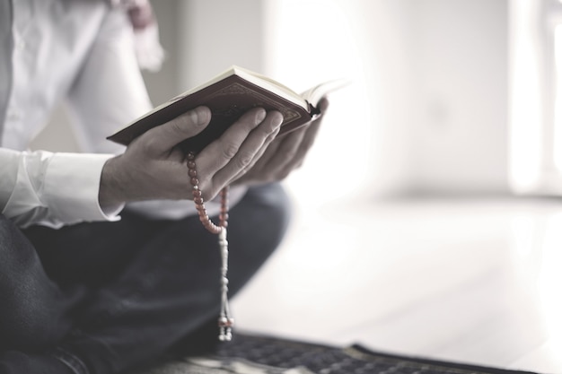 Young Muslim man reading Koran, indoors