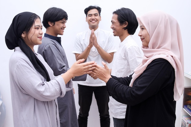 Young muslim people hand shaking, asking for apologize during eid mubarak moment.