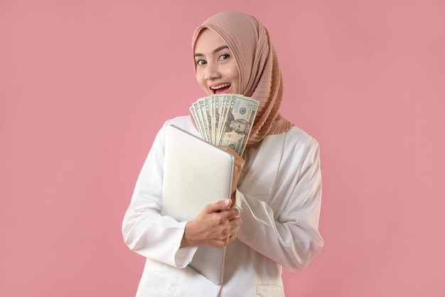 Young muslim woman hold money and laptop on isolated background