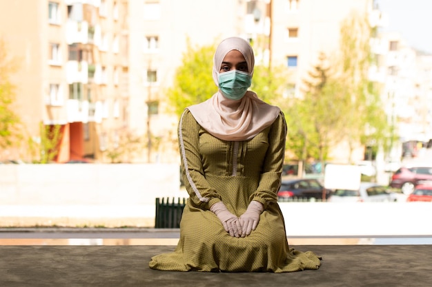 Young Muslim Woman Praying Outdoors Wearing Protective Mask and Gloves