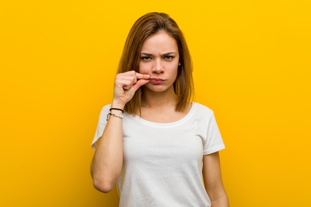 Young natural caucasian woman with fingers on lips keeping a secret.