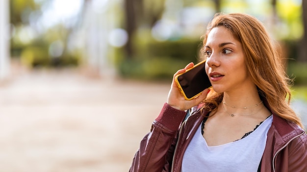 Young natural girl talking with her smartphone in the park