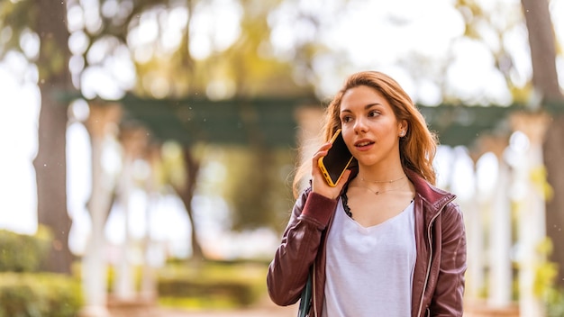 Young natural girl talks with her smartphone in the park