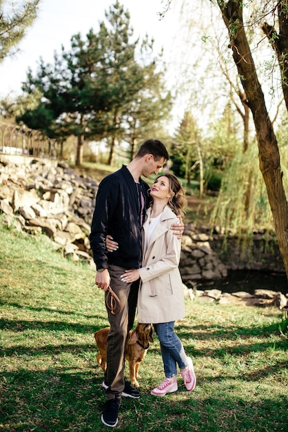 Young newlywed couple is kissing while holding their cocker spaniel puppy outdoors in autumn.