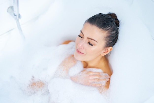 Young nice brunette woman having bath in bathtub High quality photo