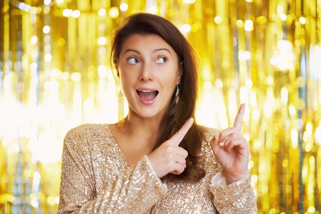 Young nice woman at party over gold background