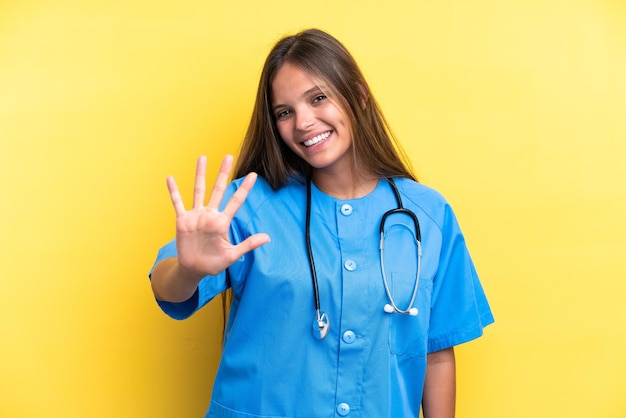 Young nurse caucasian woman isolated on yellow background counting five with fingers