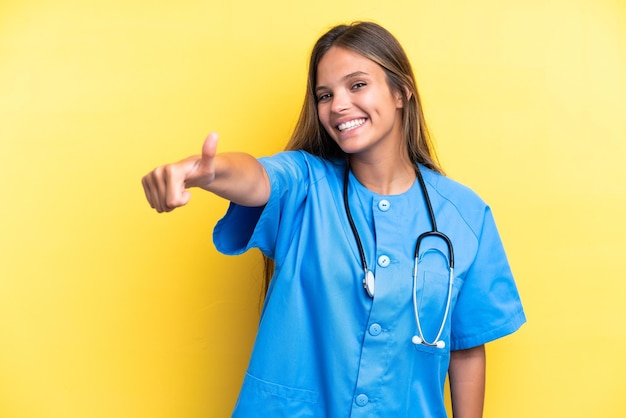 Young nurse caucasian woman isolated on yellow background giving a thumbs up gesture